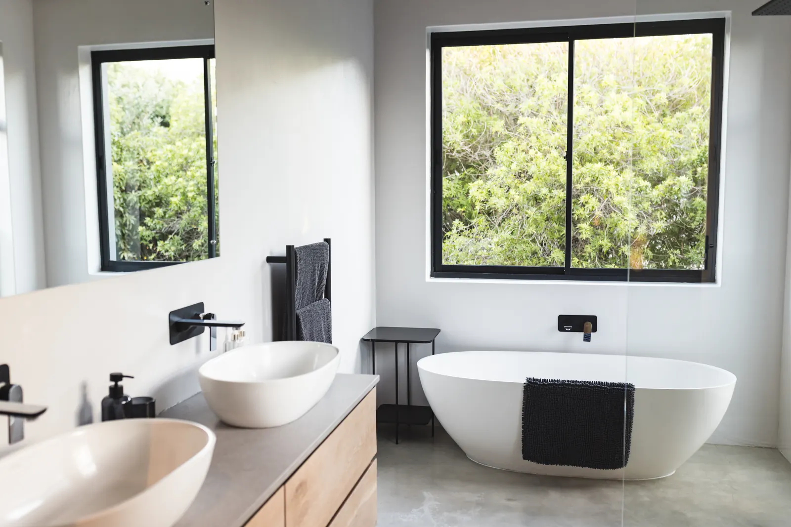 Stone vessel sinks and a freestanding tub under a garden window