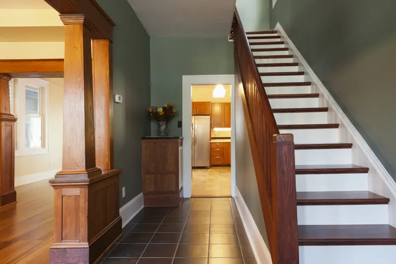 Foyer with a built-in column, wood trim and a painted staircase