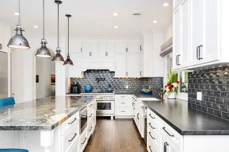 White shaker cabinets with a charcoal subway-tile backsplash and pendant lights