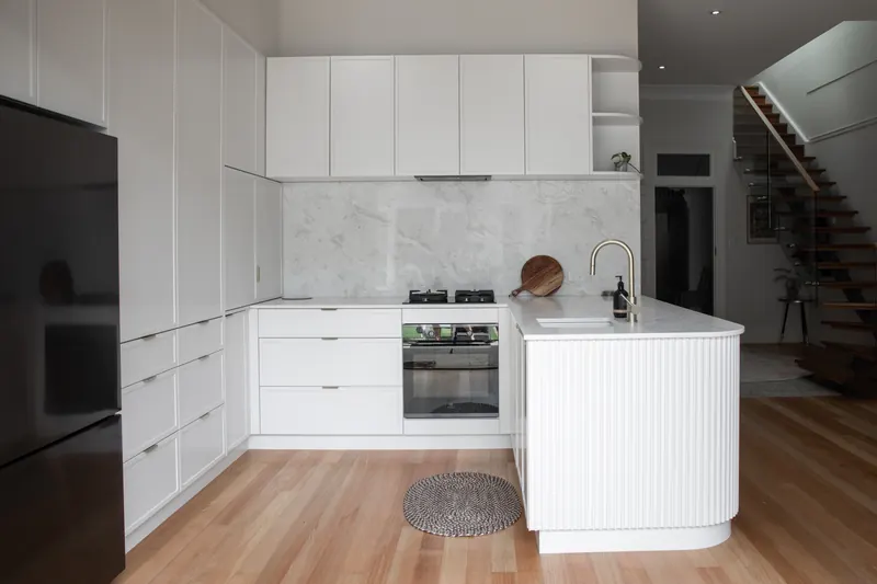 Handleless white kitchen with a fluted island and marble backsplash
