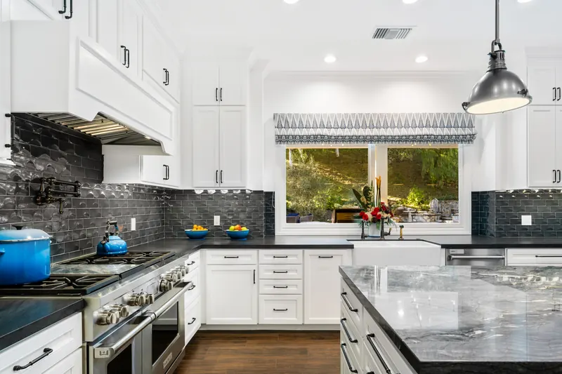 Farmhouse kitchen with dark tile backsplash and a window over the sink