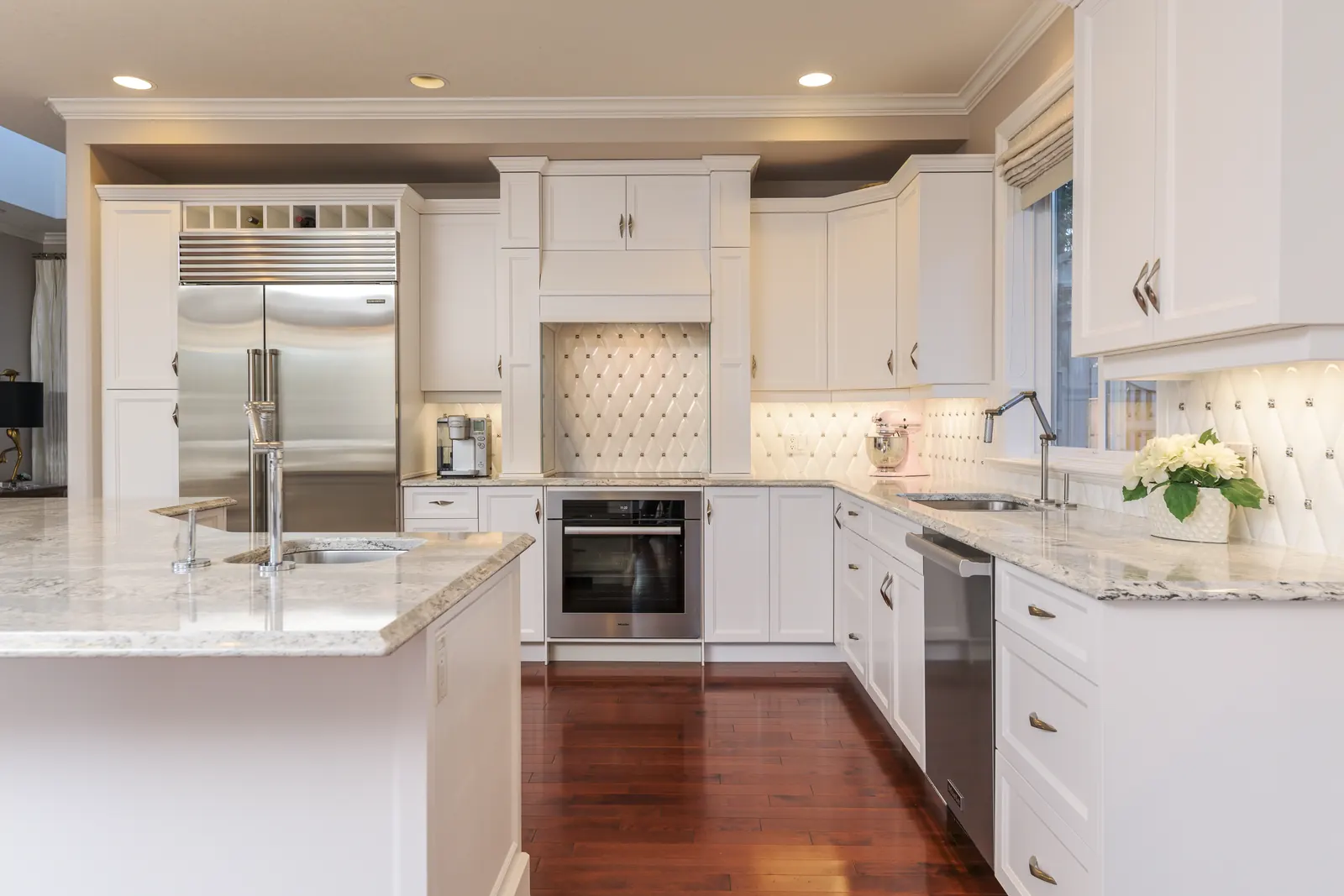 Cream cabinetry with marble counters and cherry hardwood floors